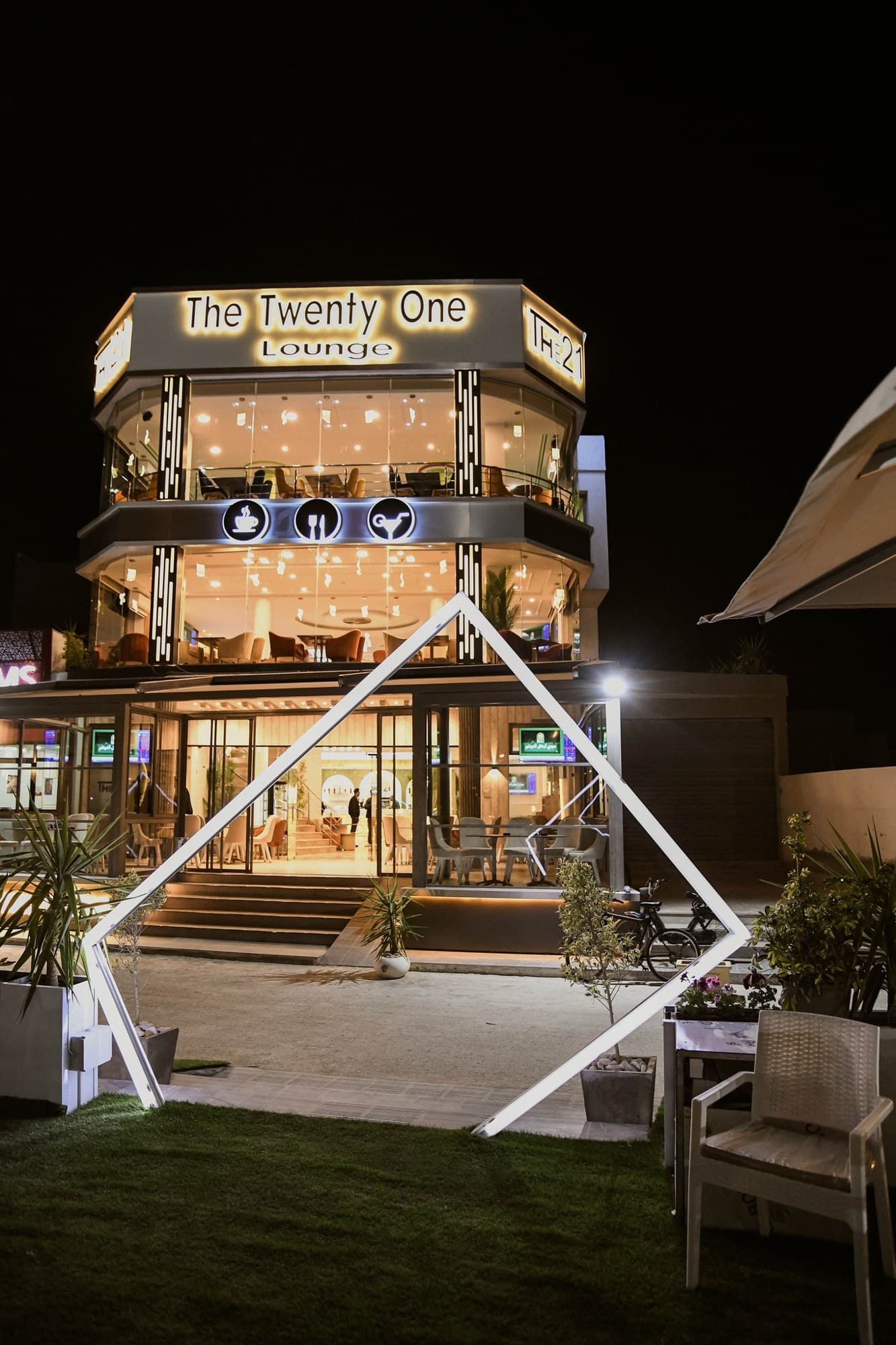 La façade du The Twenty One Lounge illuminée, vue depuis le jardin