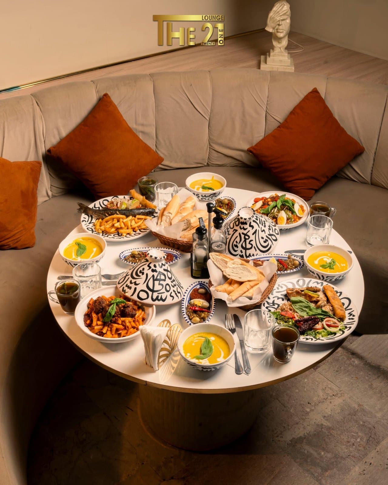Grande table ronde couverte de plats à partager dans le salon