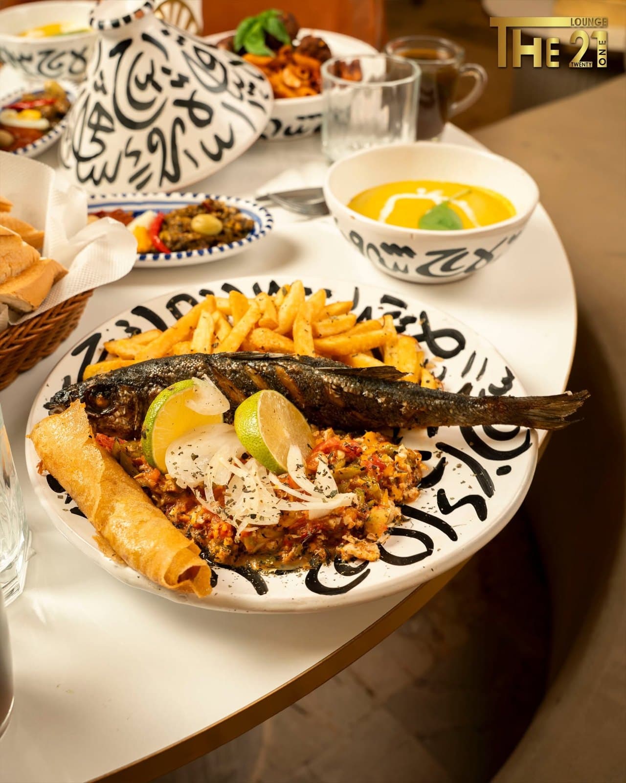 Poisson entier grillé servi avec du riz, des légumes et des bricks