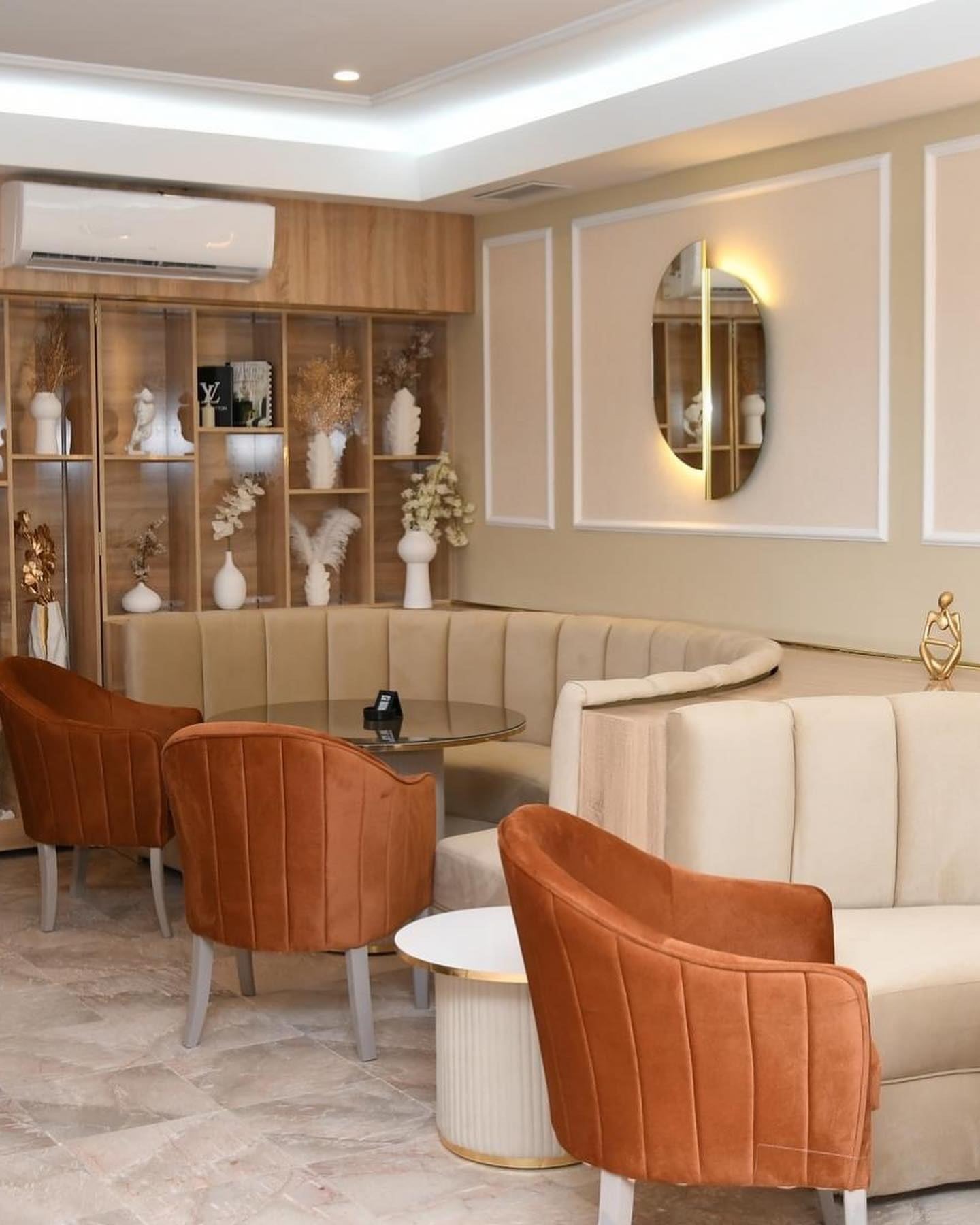 Le salon du The 21 : fauteuils en velours terracotta, banquettes crème et bibliothèque décorative