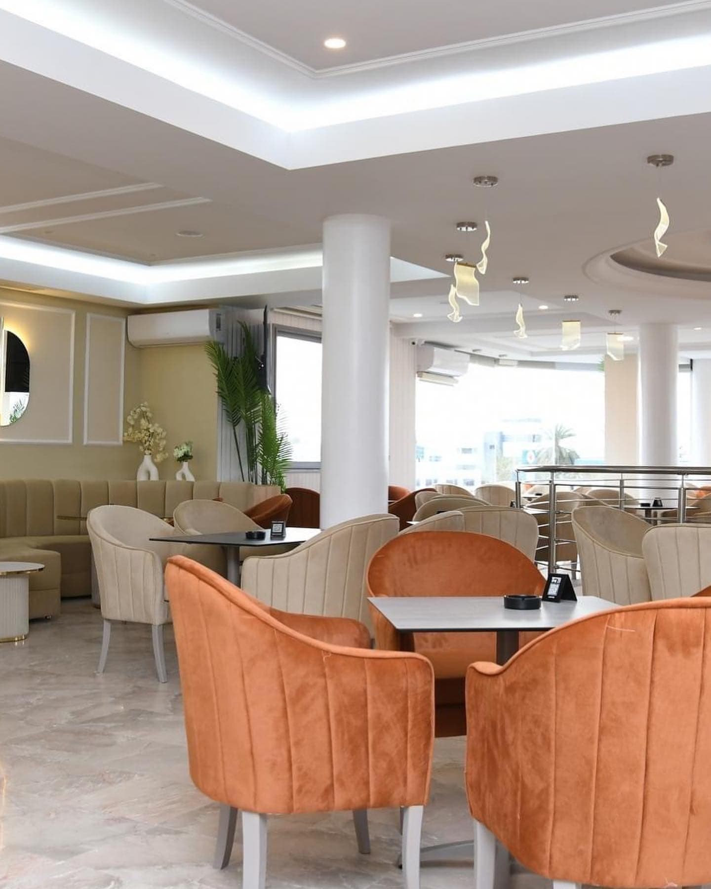 Grande salle lumineuse du The 21, fauteuils en velours et banquettes crème
