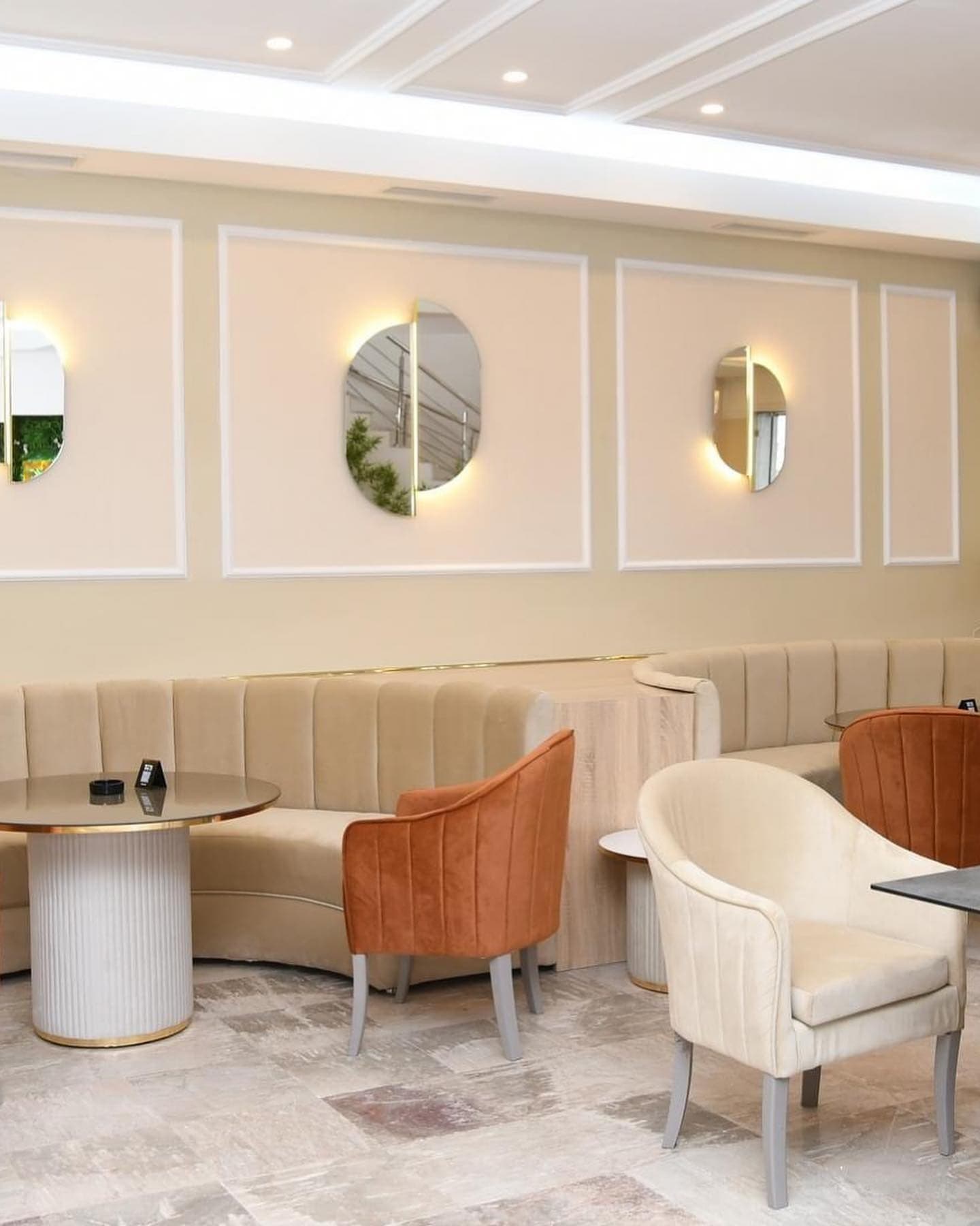 Mur crème aux miroirs ovales rétroéclairés et fauteuils en velours